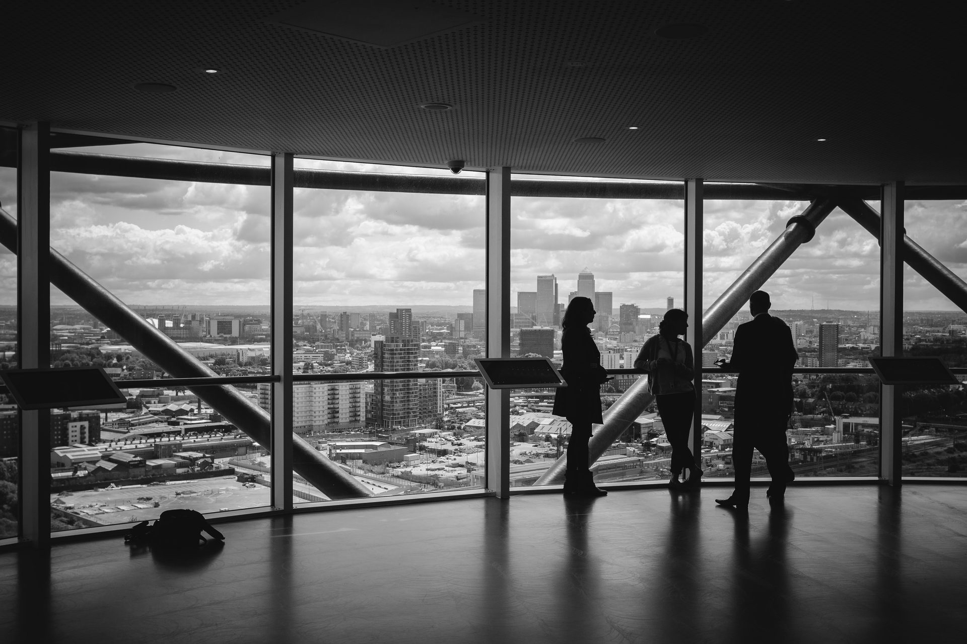 Professionals in conversation at a high-rise office window overlooking a city skyline